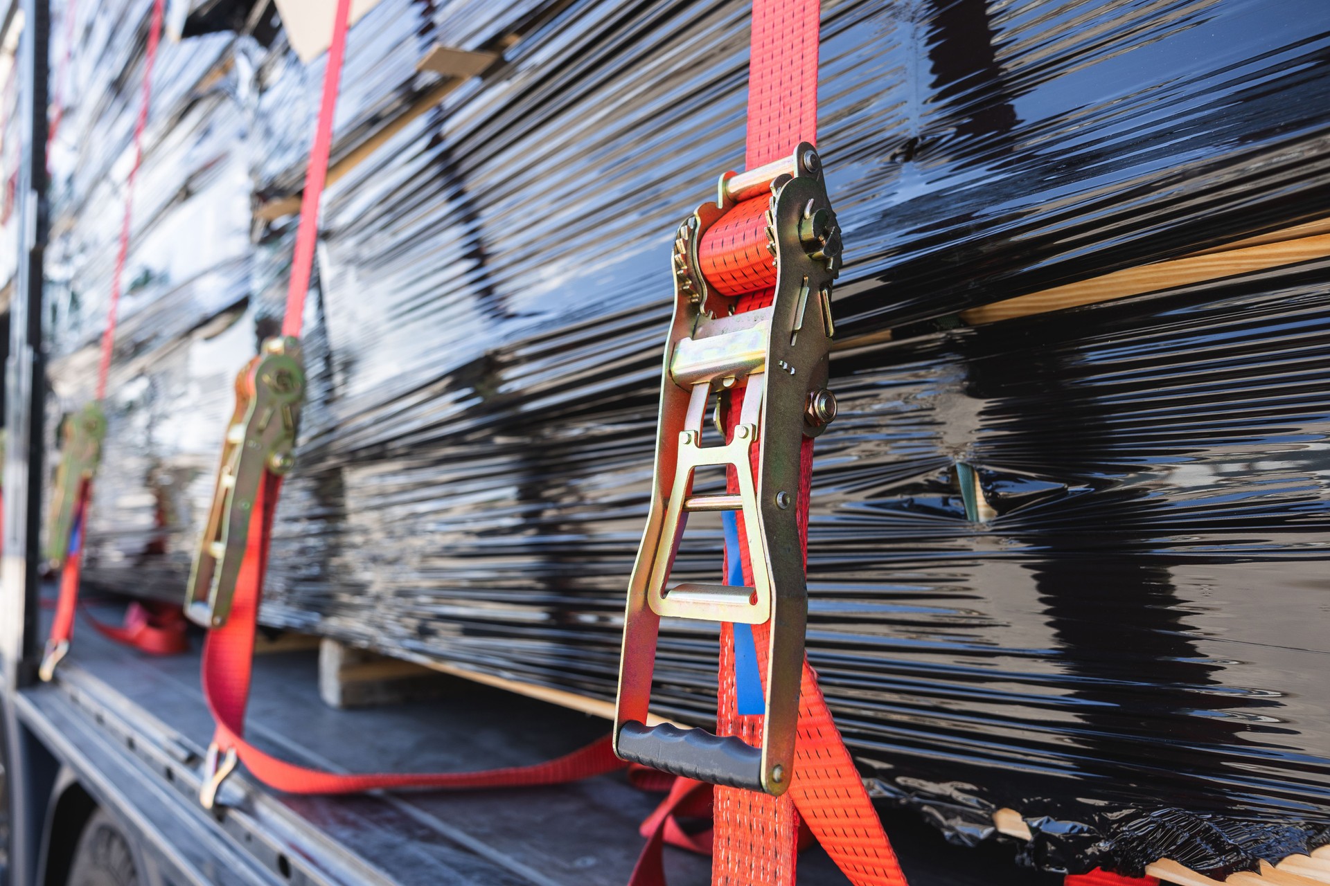 Secure cargo transport: Red ratchet strap on delivery truck.